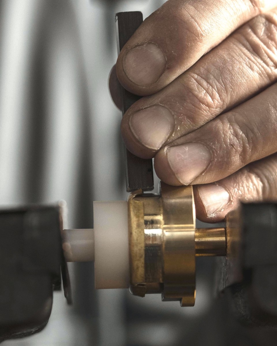 Hand polishing a metal watch component on a rotating tool.