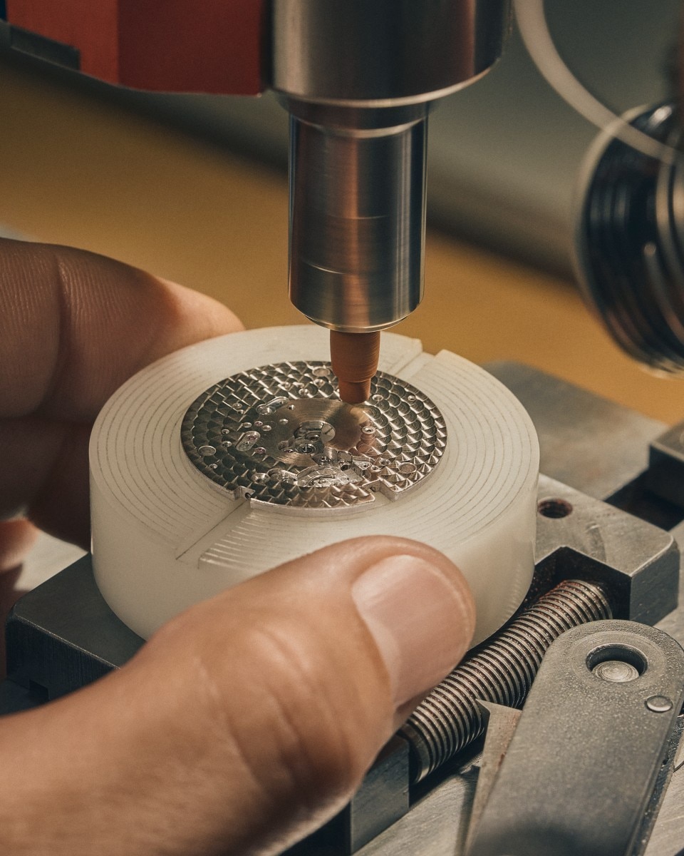 Close-up of a machine drilling a circular pattern onto a light-colored object held by a person's hand