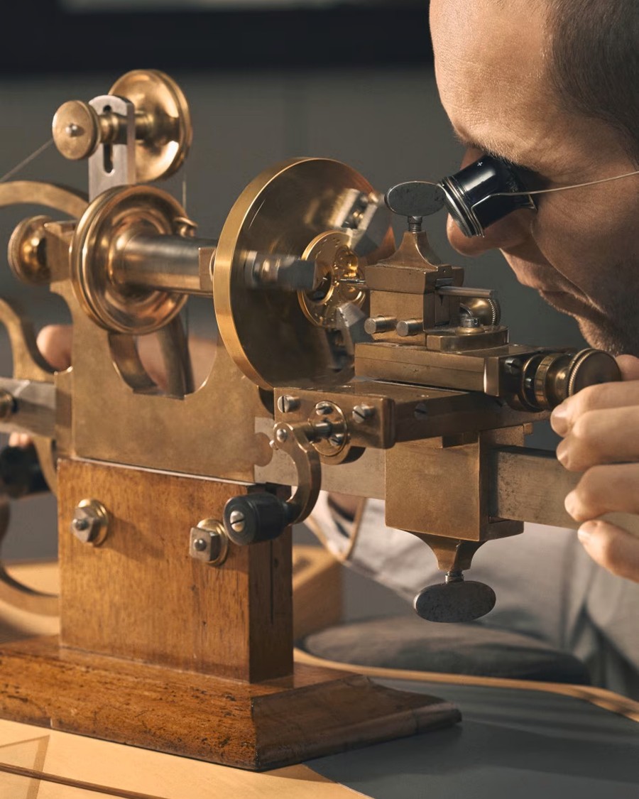 A watchmaker creates a luxury wristwatch on a special machine.