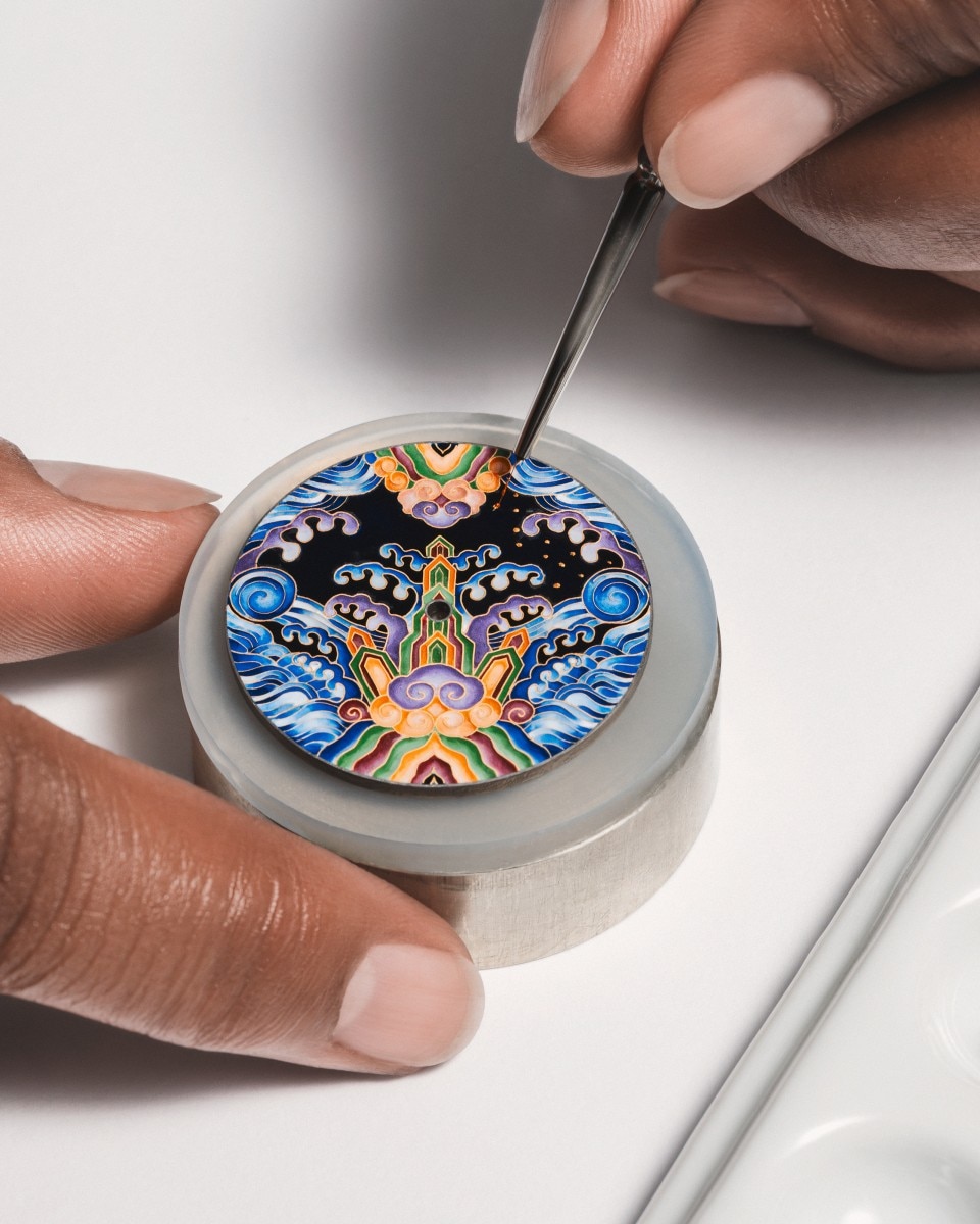 Close-up of an artist painting a vibrant enamel watch dial by hand.