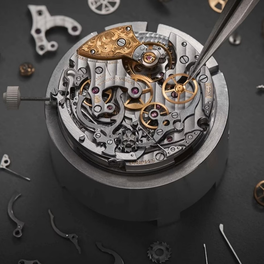 The intricate inner workings of a mechanical watch movement with gears and springs, being manipulated by tweezers.