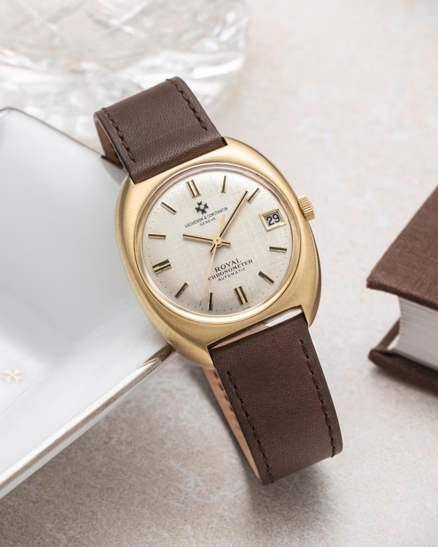 A watch with a round golden case and a brown leather strap.