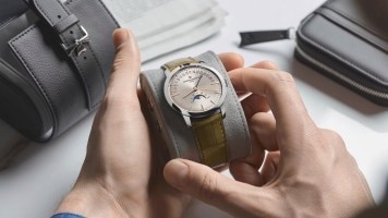 Two hands unpacking Vacheron Constantin watch with leather strap and silver bezel and details